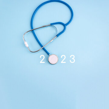 Medicine stethoscope and numbers 2023 on blue background. Happy New Year medical calendar cover. Square banner.