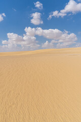 Image of the Sahara desert in Egypt, with yellow sand, and dunes, on a sunny day with clouds