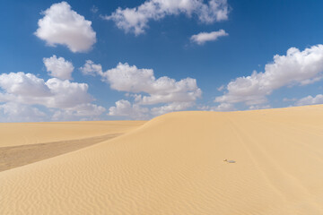 Image of the Sahara desert in Egypt, with yellow sand, and dunes, on a sunny day with clouds