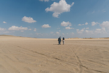 A young couple walking alone through the Fayoum desert in Egypt.