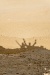 Fototapeta na wymiar Shadow of two people on top of a rock formation in the Faiyum desert in Egypt.