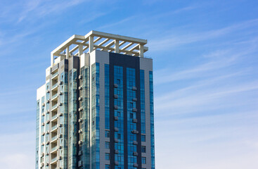 Modern high-rise apartment building at the blue sky background. Investment in ready construction site. Office, business premises for rent. Skyscraper in a big city financial center. Place for text.