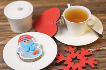 Christmas gingerbread, tea in a white cup, wooden heart, wooden table. Selective focus.
