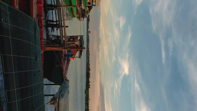 View of fishing boats moored in the riverfront at dusk in Kampot, Cambodia