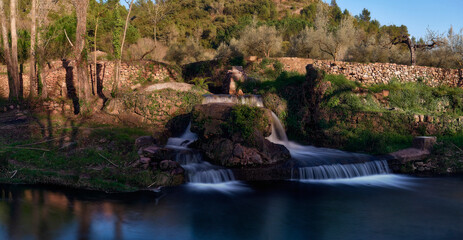 Fototapeta na wymiar Small waterfalls over a stream on a sunny day