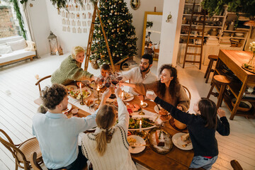 Top view of cheerful family clinking glasses during traditional Christmas dinner