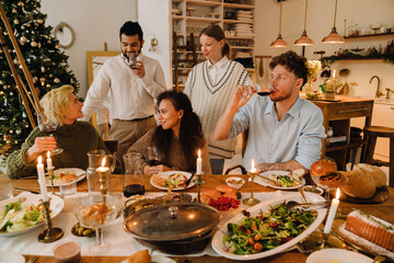 Group of joyful friends having traditional dinner together during Christmas holidays