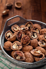 Organic walnuts in a bowl on a wooden backgound.