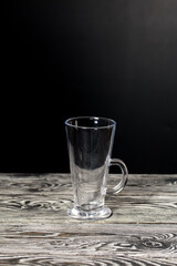 Empty glass goblet. Stands on black pine boards. On a black background.