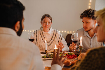Group of cheerful friends having Christmas dinner together at home