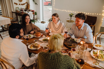 Group of cheerful friends having Christmas dinner together at home