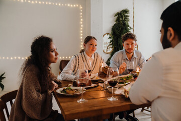 Group of friends talking while having traditional Christmas dinner