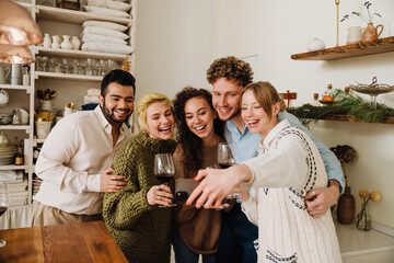 Group of smiling friends taking selfie while spending time together during Christmas holidays