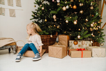 Obraz na płótnie Canvas Cute girl sitting on floor near Christmas tree