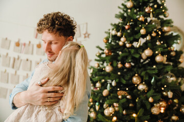 Father hugging his little daughter while spending time together near Christmas tree
