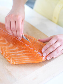 Woman using Tweezers to Remove Bones from Salmon