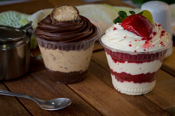 Mousse and pot cake, chocolate, strawberry and other creams, sugared strawberry, with chocolate bonbon, spoon, fabric, rustic wood
