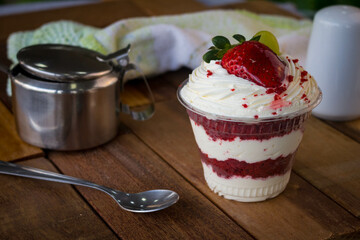 Mousse and pot cake, chocolate, strawberry and other creams, sugared strawberry, with chocolate bonbon, spoon, fabric, rustic wood