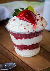 Mousse and pot cake, chocolate, strawberry and other creams, sugared strawberry, with chocolate bonbon, spoon, fabric, rustic wood