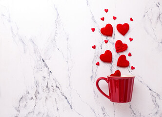 Valentines day flat lay . Big and small red hearts  and red cup on  white marble background.  Top view. Place for text.
