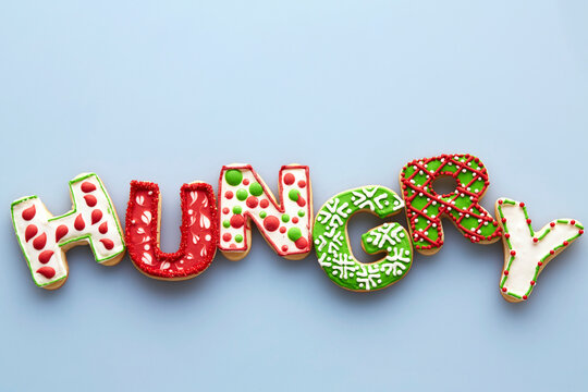 Overhead View of Christmas Sugar Cookies spelling HUNGRY on Blue Background