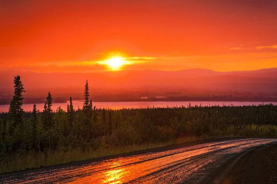 Bright red sunset at Yukon River, Dalton Highway, Arctic Alaska in summertime; Alaska, United States of America