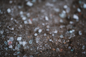 macro ground level closeup view of rock salt ice-melt on concrete with a frozen layer. 