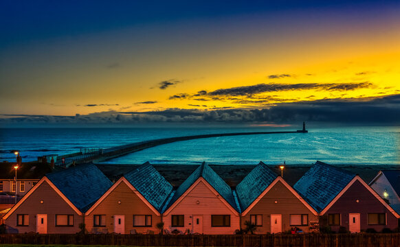 Row of Houses illuminated at sunset with Roker Pier Lighthouse in the distance, Sunderland, England