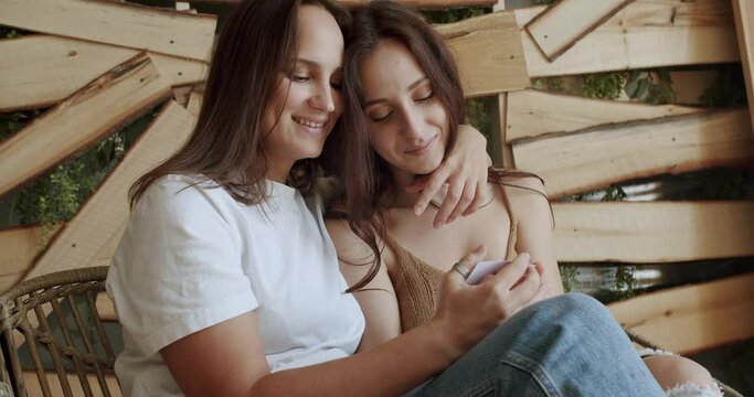 Women Lgbt Couple rest at home. Happiness of motherhood, Lesbians waiting for baby Embracing and looking at ultrasound picture. Two women sharing love and support holding hands. LGBT concept