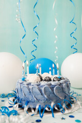 Blue birthday cake with candles and white and navy air balloons, happy birthday vertical card