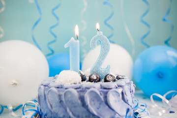 Happy twelfth birthday card with navy cake and number twelve candle with blue balloons and decoration