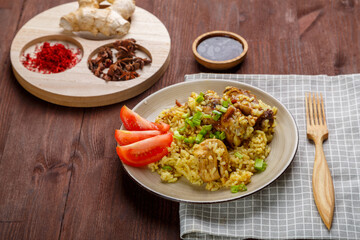 Chicken rice in teriyaki and soy sauce garnished with green onions and tomatoes in a plate.