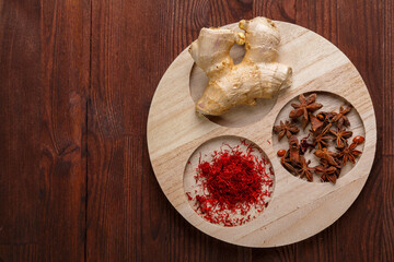 Spices ginger, saffron and anise on a round wooden bowl on the table.copy space