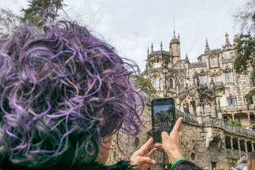 Rear View Of A Female Tourist Taking A Picture With Her Smart phone Of The Regaleira Palace Located...