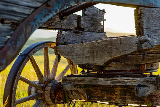 Abstract angle of an old wooden wagon sitting in a field backlit by the sunlight; Waterton Lakes National Park Area, Alberta, Canada