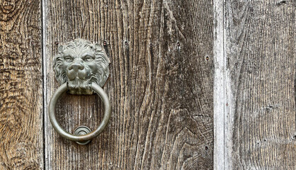 Metal lion head door knocker on an old wooden door
