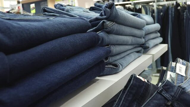 Neat stacks of folded jeans on the shop shelves in the showroom or store. 