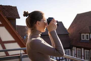 Young woman taking pictures on the camera on the street