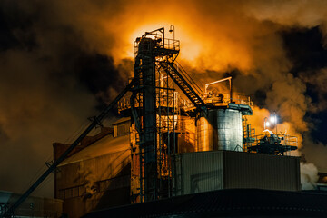 Processing plant with emissions glowing with orange light at night; Nebraska, United States of America