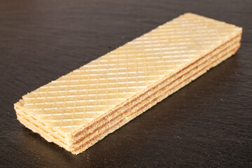 One sweet chocolate wafer on a slate stone, close-up.