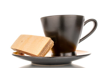 One sweet chocolate wafer with black ceramic saucer and cup, close-up, isolated on white background.
