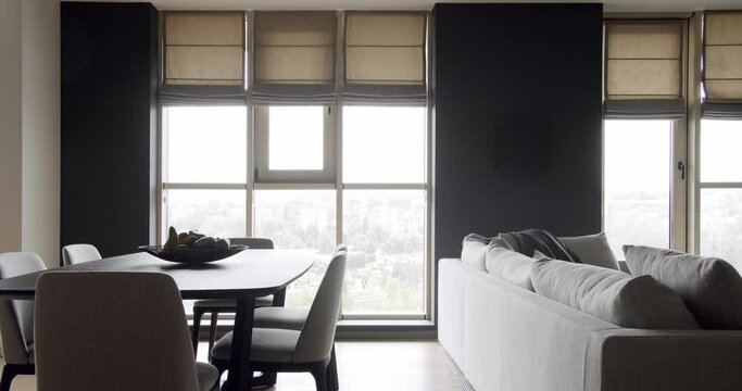 Minimalist living room with wooden table and chairs and gray furniture. Luxury Modern House Interior With Corner Sofa and Bookshelf. Fashionable furniture. Minimalist Home Interior.Luxury Elegant Room