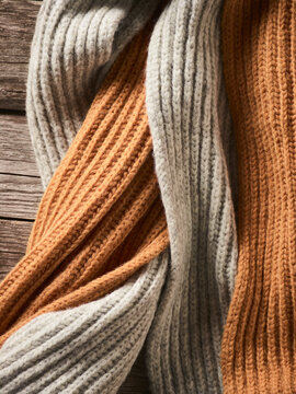 Close-up Of Neutral Coloured Knit Garments Laying On A Wooden Table; Studio