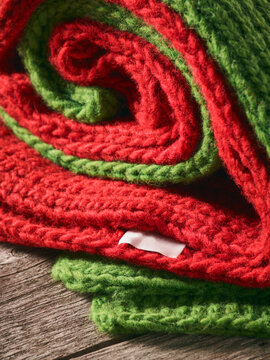 Close-up of a red and green knitted garments folded together and laying on a wooden table; Studio
