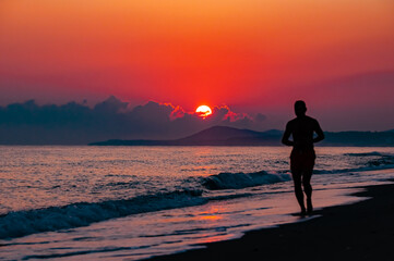 person walking on the beach at sunset