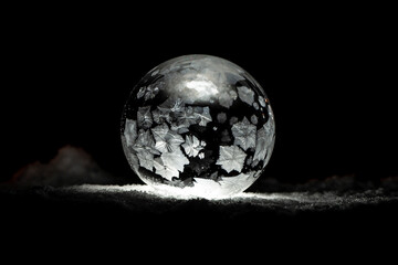 Ice crystals in a bubble illuminated on snow in black and white; Alberta, Canada