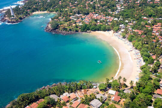 Aerial view of the rooftops of buildings surrounding the bay with a lighthouse on the headland along the coast of the Indian Ocean; Kurunduwatte Junction, Matara District, Southern Province, Sri Lanka