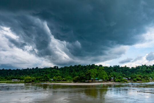 Storm clouds forming over the riverside village along the jungle covered banks of the Ayeyarwady (Irrawaddy) River; Rural Jungle, Kachin, Myanmar (Burma)