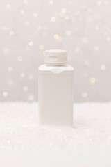 Christmas pharmacy white bottle, container of pills, tablets,drugs in snow with Christmas,New Year lightening bokeh on background. Winter holidays, medical concept. Copy space, vertical