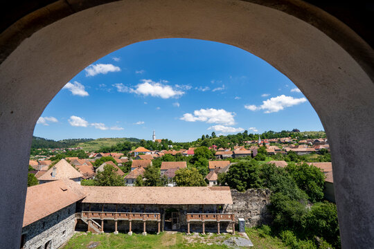 View of the town and the Cetatea Bethlen Medieval Castle of Racos through an archway; Racos, Transylvania, Romania
